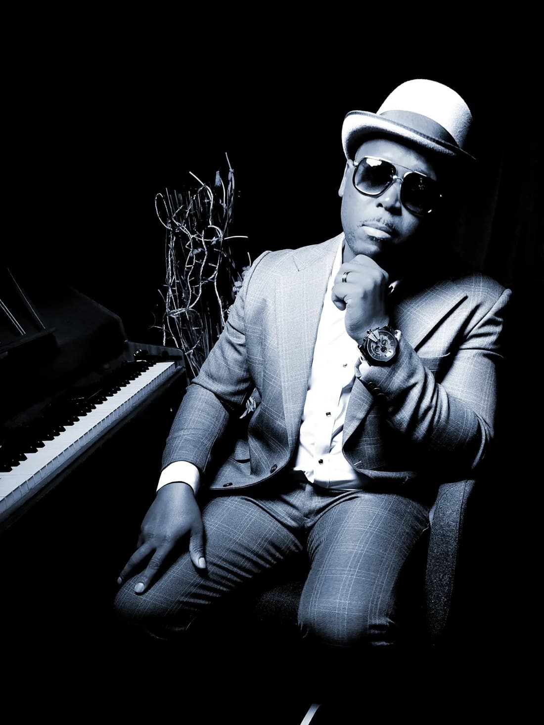 Serge Tebu at the piano in a hat and sunglasses, portrait in black and white