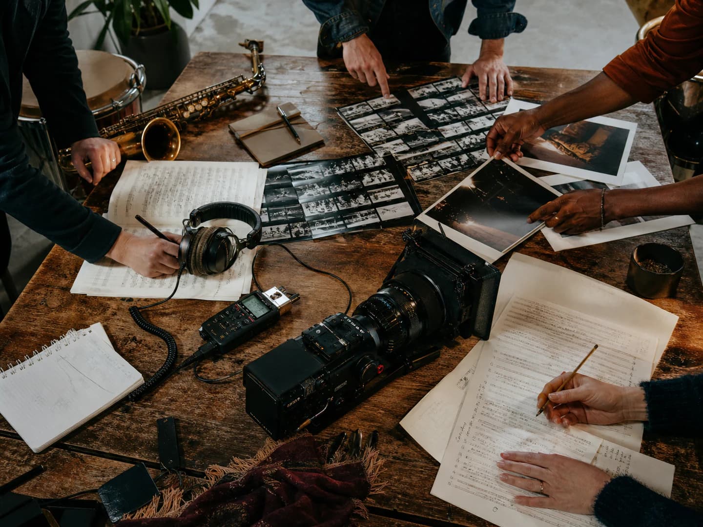 Collaborators arranging music, film and audio materials around a studio worktable